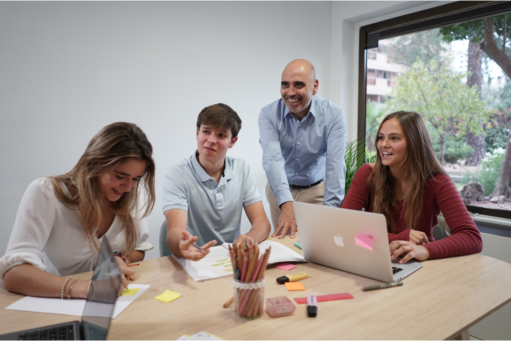 profesor y 3 alumnas en una mesa de trabajo